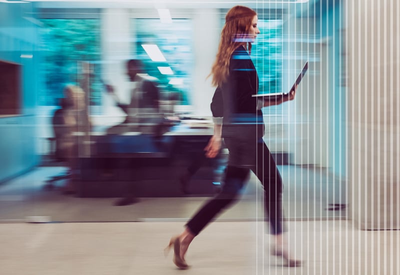 Woman walking through office with laptop